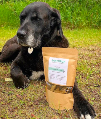 A dog sitting with Earth Pup Pet food treats